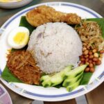 Delicious Nasi Lemak served with fried chicken, sambal, peanuts, and boiled egg.